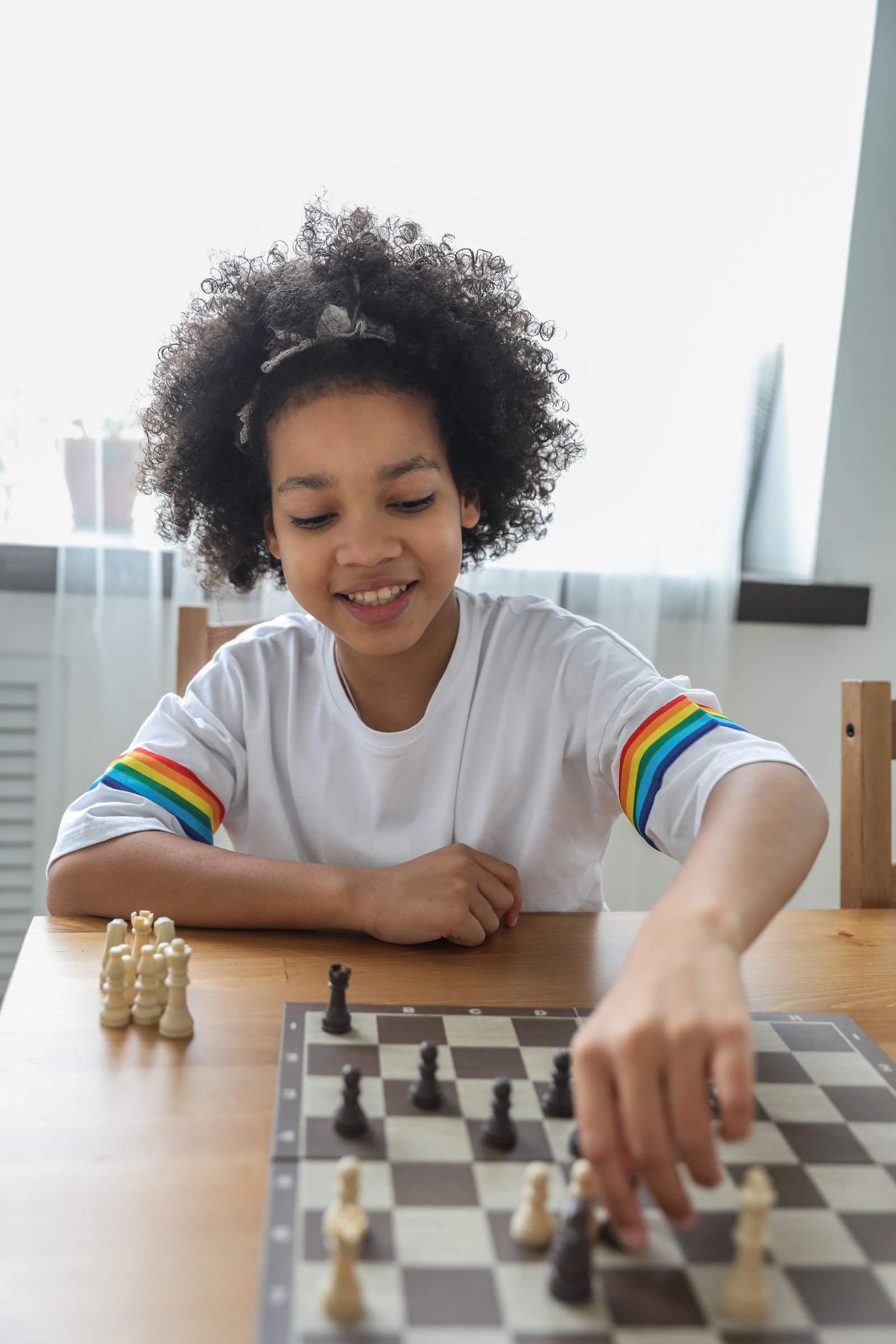 A young girl smiling as she moves a piece during a PCR Inc. Chess for Peace night in Boston
