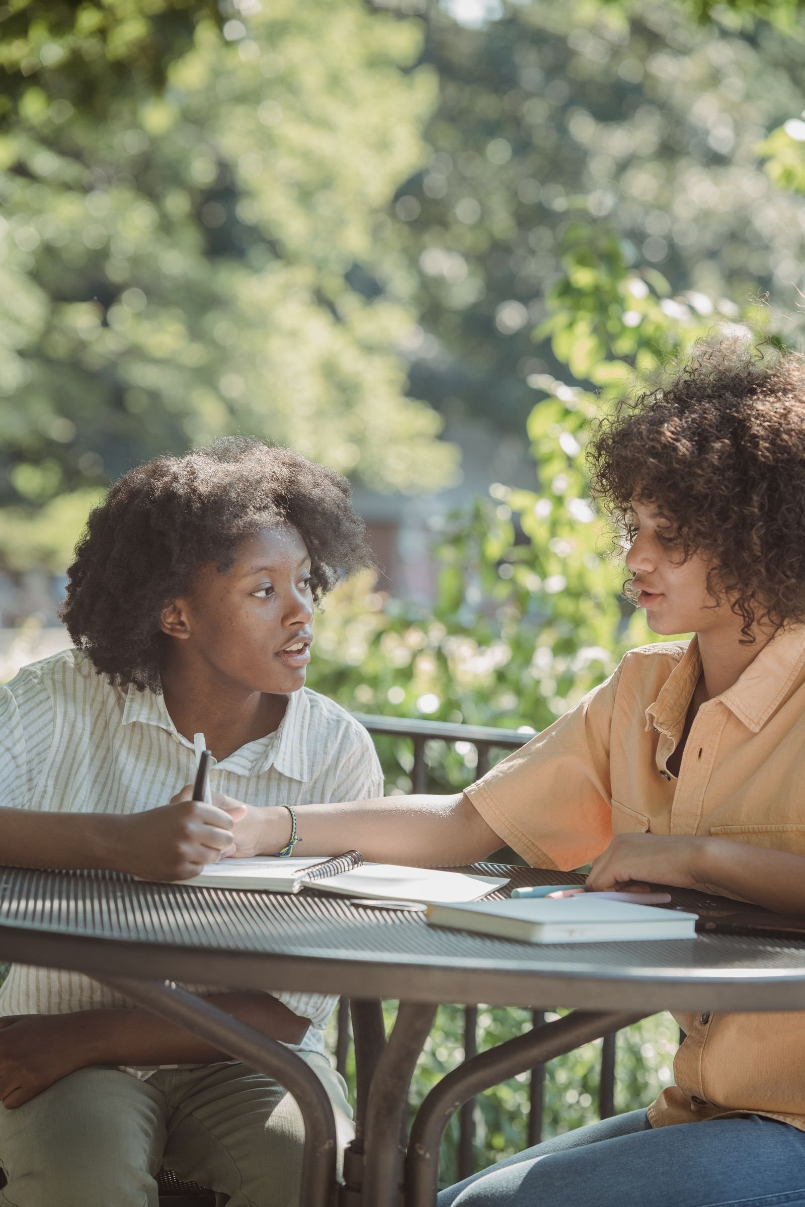 Two young people in conversation at an outdoor table